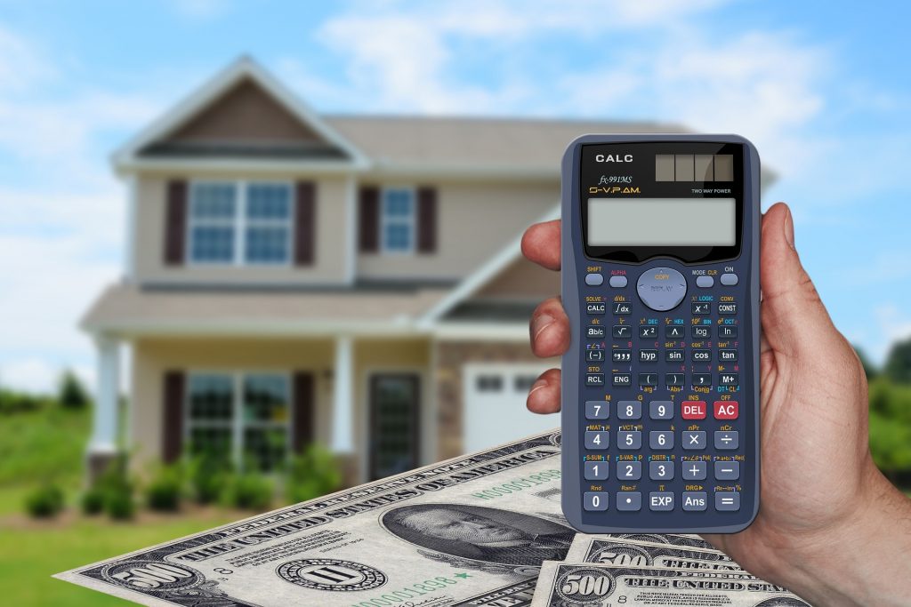 House in background with person holding calculator